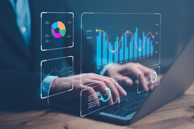 hands at laptop with bar charts and graphs