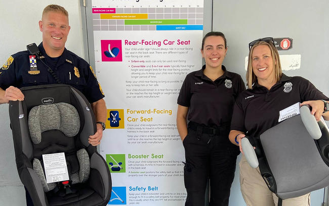 3 officers holding carseats