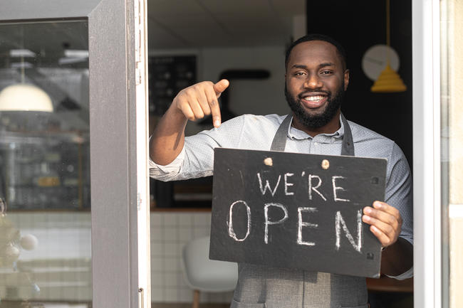 Man holding &quot;We're open&quot; sign